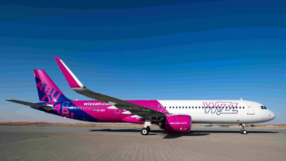 Wizz Air Abu Dhabi aircraft on runway in desert backdrop under clear sky.