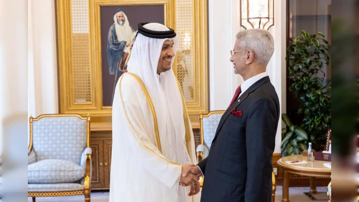 A senior Indian official shakes hands with a Qatari leader during a meeting in an ornate room.