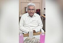 Image shows man in a white shirt with cash and bottles with pink fluid.