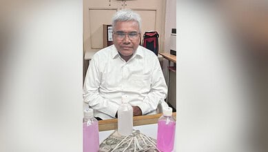 Image shows man in a white shirt with cash and bottles with pink fluid.