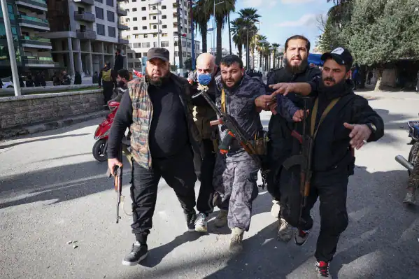 Injured police officer escorted away after clashes in Latakia.