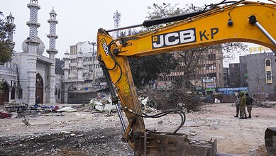 An excavator used in demolition of alleged encroachments stands amid rubble after the demolition of alleged encroachments on land adjoining the mosque, carried out by the Municipal Corporation of Delhi
