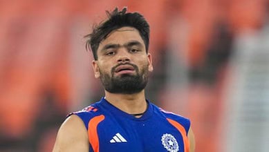 Cricket player celebrating on the field in a blue jersey with orange accents.