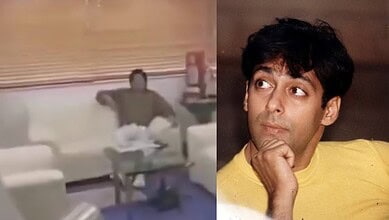 Man relaxing on a sofa in a modern living room with a large window and decorative items.