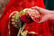 Up of a handshake between bride and groom, highlighting traditional wedding attire and henna designs.