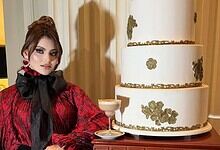 Expensive cake worth Rs 16 crore with gold accents, displayed with a woman in elegant attire.