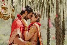 Vijay and Rashmika share a joyful moment at their wedding, surrounded by traditional decorations and flor.