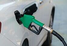 Petrol pump nozzle inserted into a car's fuel tank, promoting E20 ethanol-blended fuel at petrol stations.
