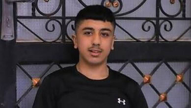 The image of Palestinian teenager Jad Jadallah standing in front of a metal gate.