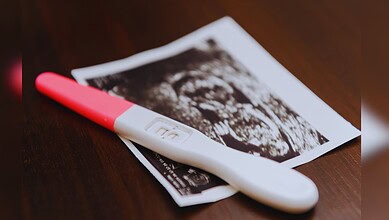 Image shows a Pregnancy test and ultrasound image on wooden surface