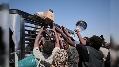 Aid workers and civilians reach for supplies from a drone strike-hit convoy in Sudan.