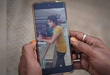 Woman with yellow shirt using smartphone at train station platform.