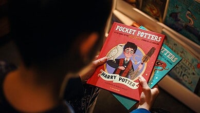Child holding 'Pocket Potters' book from Blooming India’s new series at a bookstore.