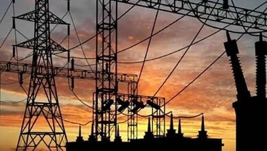 High-voltage power lines and pylons against a sunset sky in Telangana.