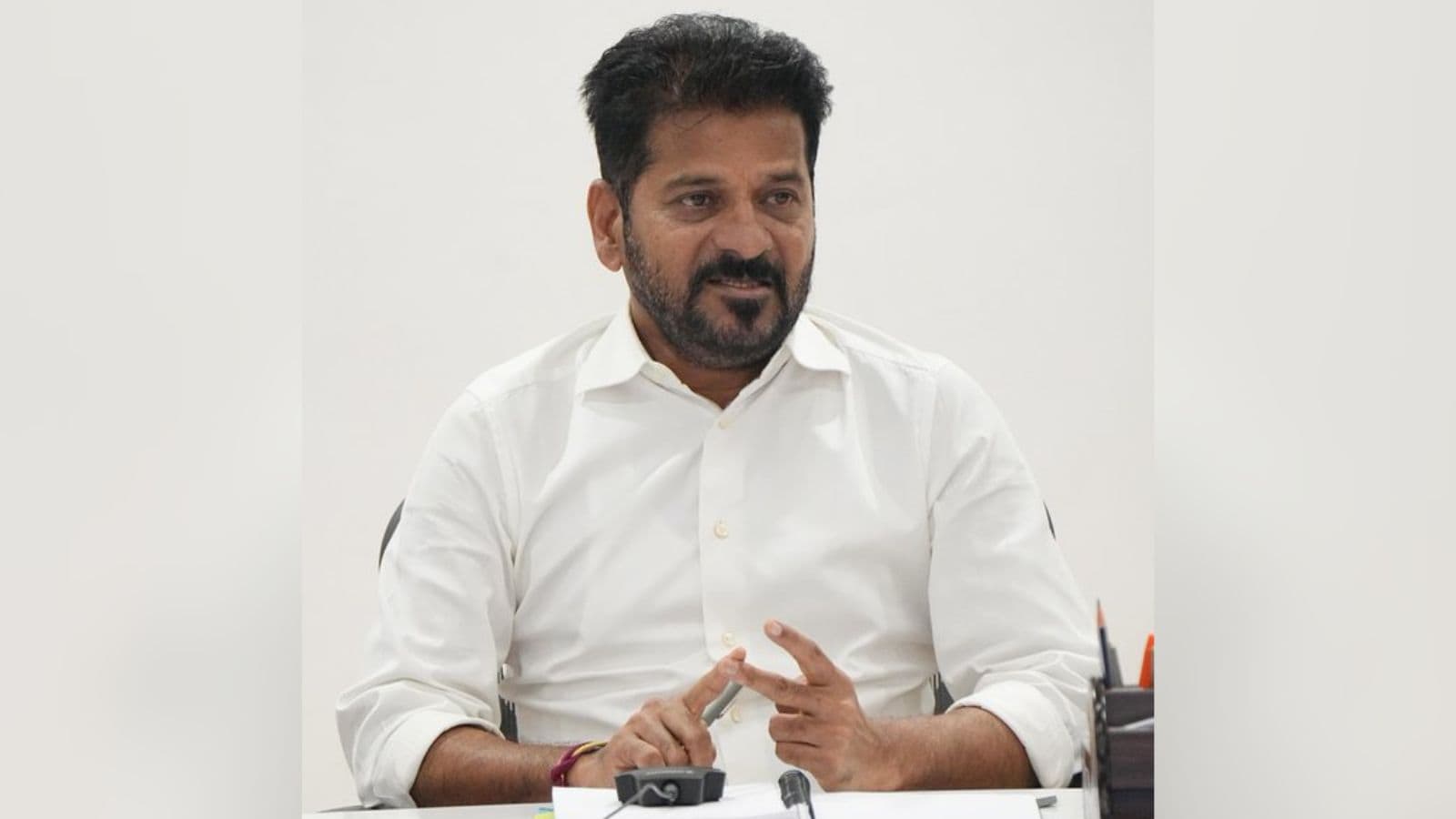 Man in white shirt speaking during a business meeting, focused on leadership and strategy.