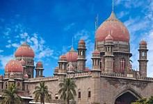 Historic Kaleshwaram palace with domes and minarets under a blue sky, surrounded by palm trees.