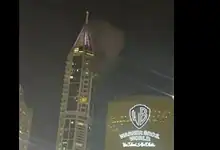 Night view of a tall building with smoke and bright lights during a conflict in Lebanon.