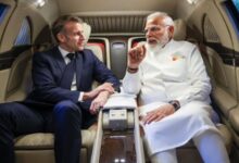 Indian Prime Minister Narendra Modi and French President Emmanuel Macron seated inside an car, engaged in conversation.