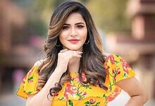 Ashu Reddy posing confidently outdoors, showcasing her vibrant attire and glamorous look.