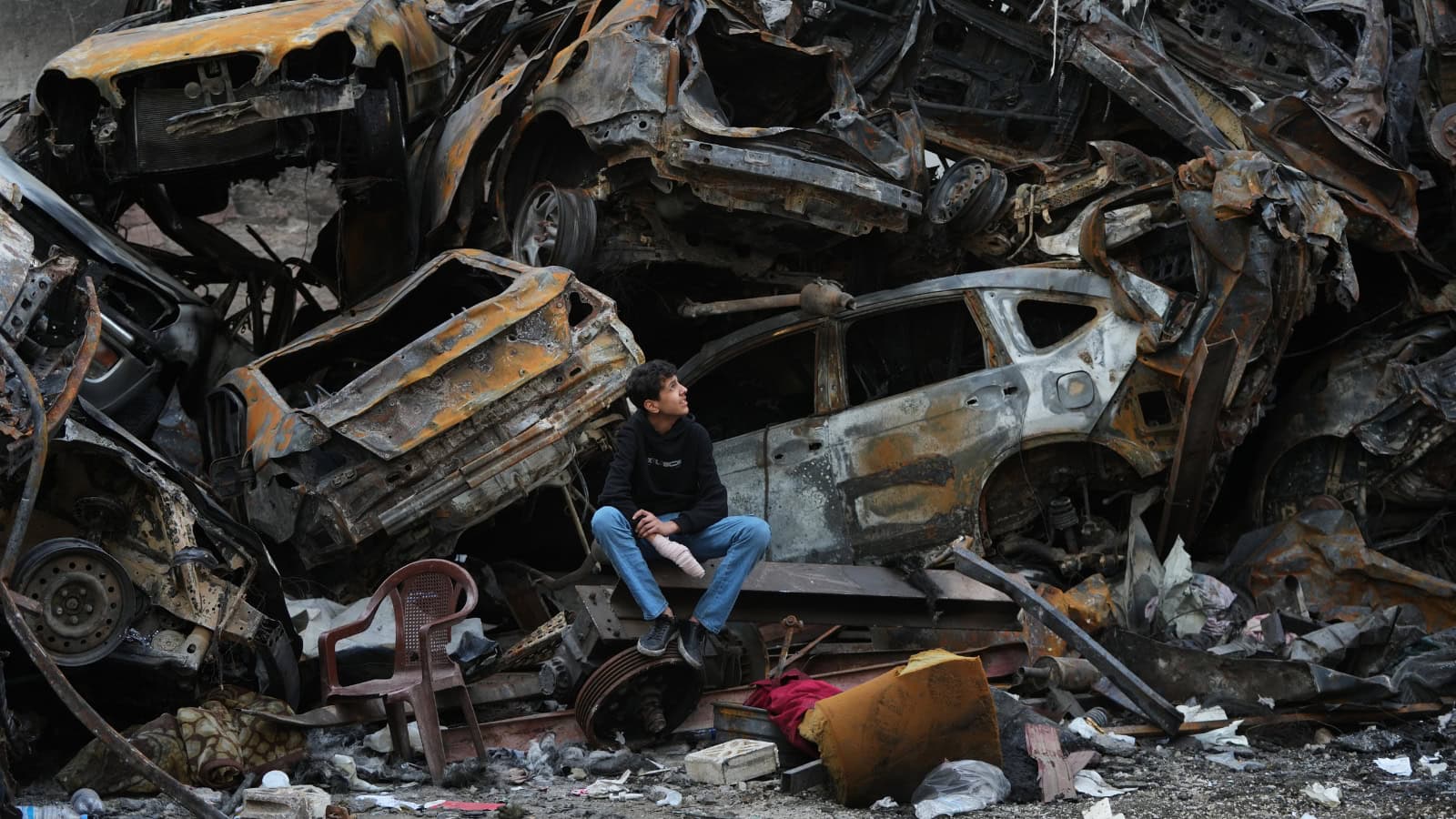 A man sits next to charred cars and wreckage where a building was destroyed by an Israeli airstrike the previous Wednesday, in central Beirut, Lebanon, on Tuesday, April 14.
