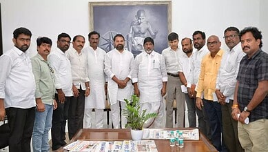 Group of men in white and casual shirts standing together in a meeting room with a framed picture on the.