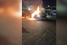 Car on fire causing traffic disruption at Narsingi TGPA rotary. Flames and smoke visible as emergency ser.