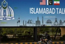 Man on motorbike passes billboard for US-Iran peace talks in Islamabad
