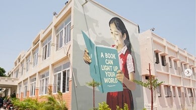 Colorful mural of a girl reading a book on the school wall, promoting education and literacy.