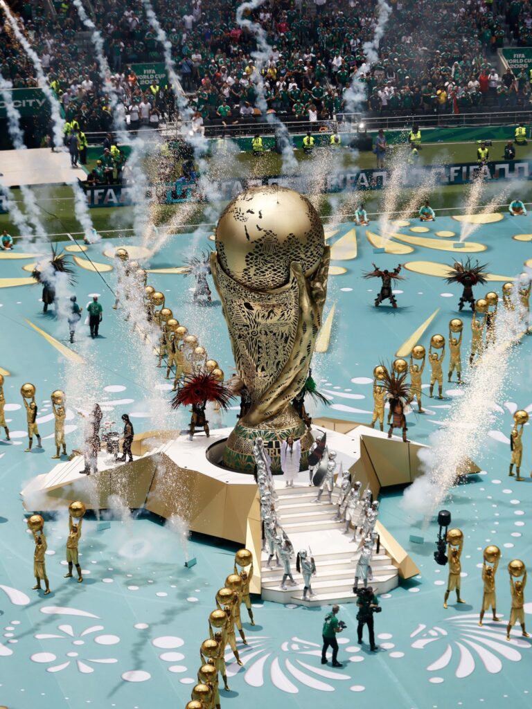 Celebratory scene with the FIFA World Cup trophy, fireworks, and fans at the stadium.