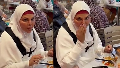 Woman in white hijab covering her head, eating food at a crowded restaurant table.
