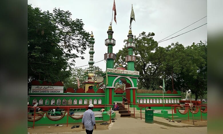 Vishweshwaraya Swamy Temple with vibrant green and red architecture, surrounded by lush trees and cloudy.