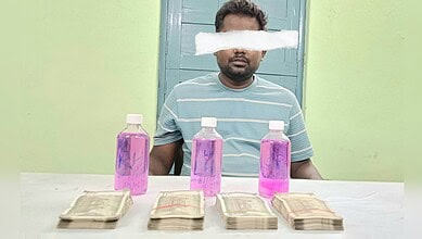 Man with a cloud over his eyes sitting at a table with pink bottles and cash.