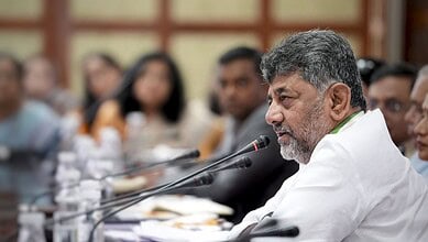 Senior man speaking at a conference with a microphone, surrounded by attentive participants in a formal s.
