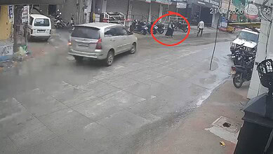 Motorcycle accident scene on Asif Nagar street with bystanders and vehicles, captured by CCTV.