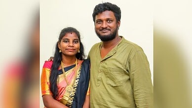 Happy couple smiling, woman in traditional saree and man in casual shirt, indoors.