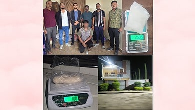 Group of men with a scale showing 253.5 grams and a house model on a digital scale.