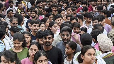 Crowd of young people gathered outdoors, many looking serious or focused.