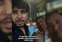 Young man speaking to camera during night, with two men in background, in a public setting.
