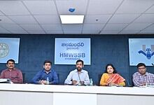 HMWSSB officials seated at a press conference in Hyderabad with banners in Telugu and English behind them.