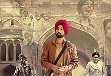 Young man in a brown leather jacket and red turban standing in front of historic architecture.