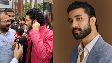 Raghav Juyal in a grey suit responds to a reporter during an interview.