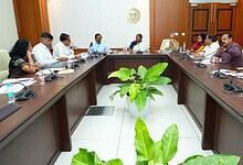 Government officials and leaders in a meeting room discussing water supply to rural areas.