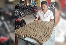 Man sitting at a table with a large collection of Rs 10 coins arranged in a grid.
