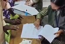 School student reviewing documents during voter list revision in Belagavi village.