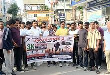 Group of people participating in a drug-free marathon awareness event on a busy street.