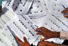 Voters' lists and ballot papers being reviewed and sorted by election officials.