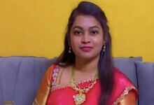 Young woman in traditional attire sitting on a sofa against a yellow wall.