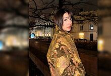 Ayeza Khan in a floral shawl, posing outdoors at night in a city setting.