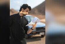 Pak actor Bilal Abbas Khan reading a script outdoors with mountains in the background.
