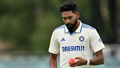 Indian cricketer in white jersey holding a pink cricket ball on the field.
